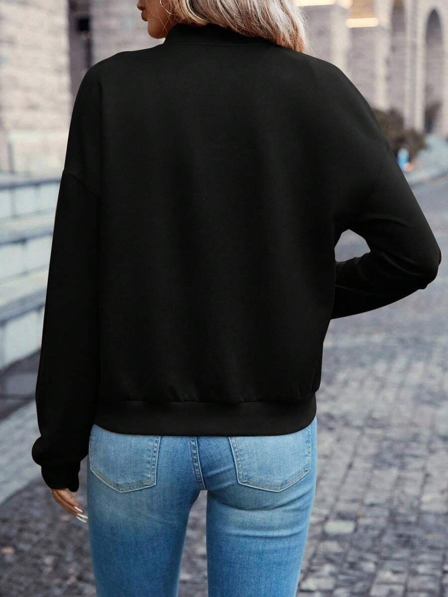 Person wearing a black jacket and blue jeans walking on a cobblestone street.