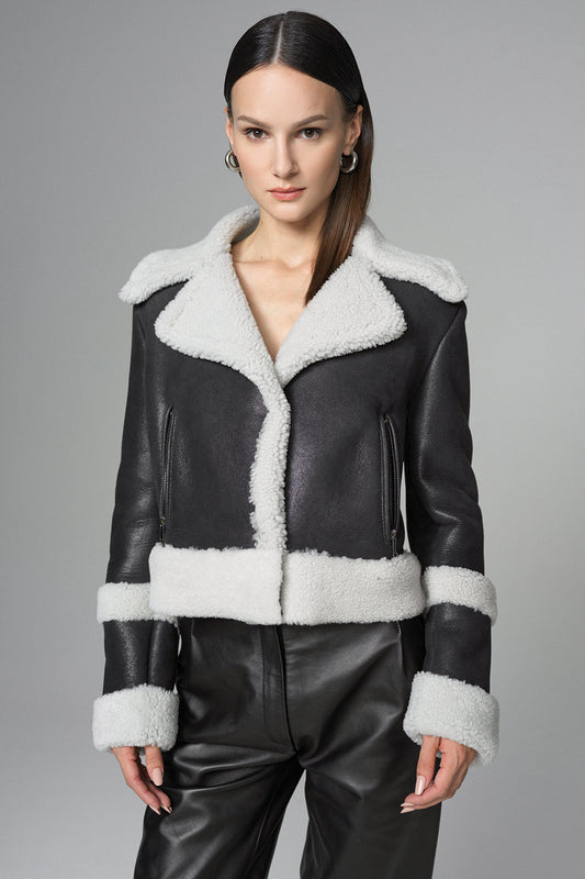 Black leather jacket with white fur trim worn by a model on a gray background