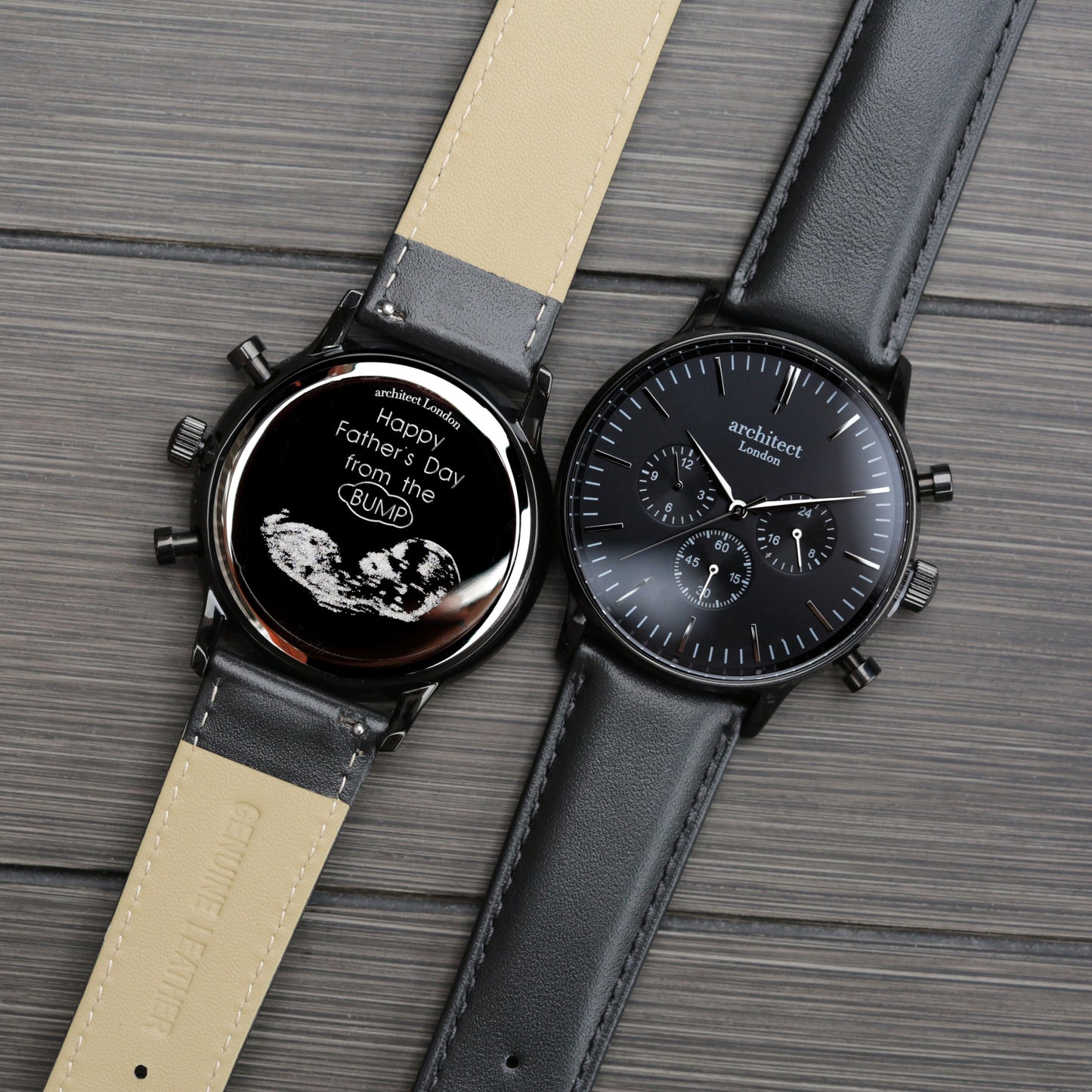 Two watches with black faces and leather straps on a wooden surface