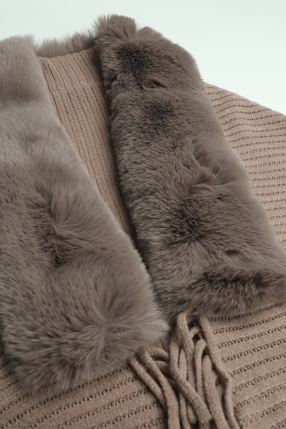 Close-up of a brown knitted garment with fur trim on a light background