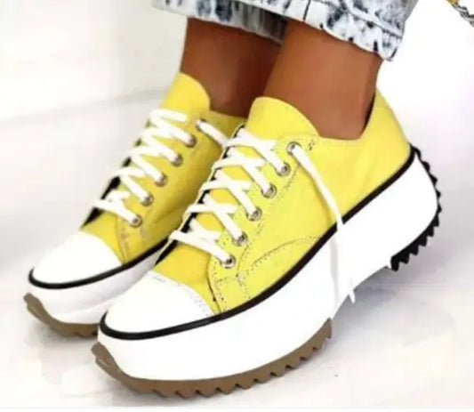 Yellow sneakers with white soles on a light background