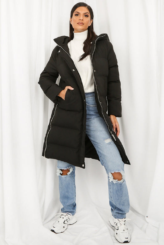 Person wearing a black puffer coat, white turtleneck, and ripped jeans on a white background