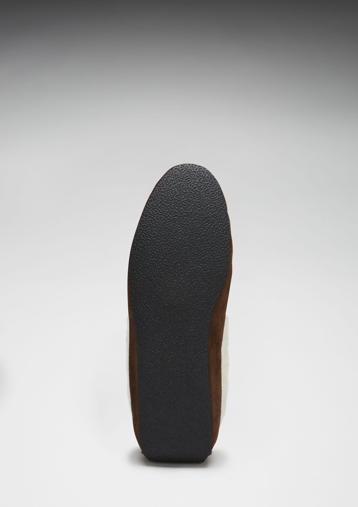 Close-up of a shoe sole with brown leather and black rubber on a white background