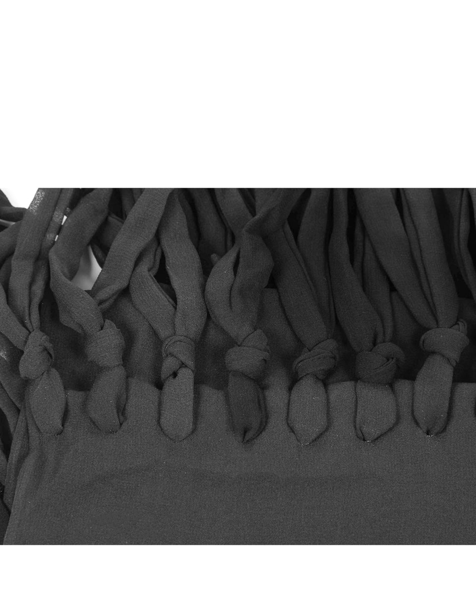 Black tassel detail on a garment against a white background