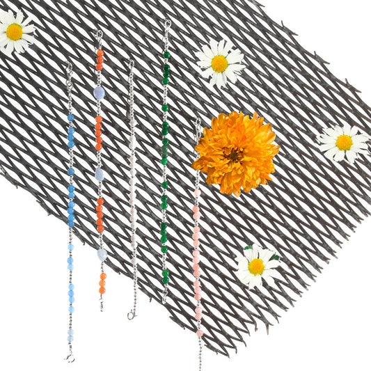 Three beaded chains with colorful beads on a textured surface with flowers.