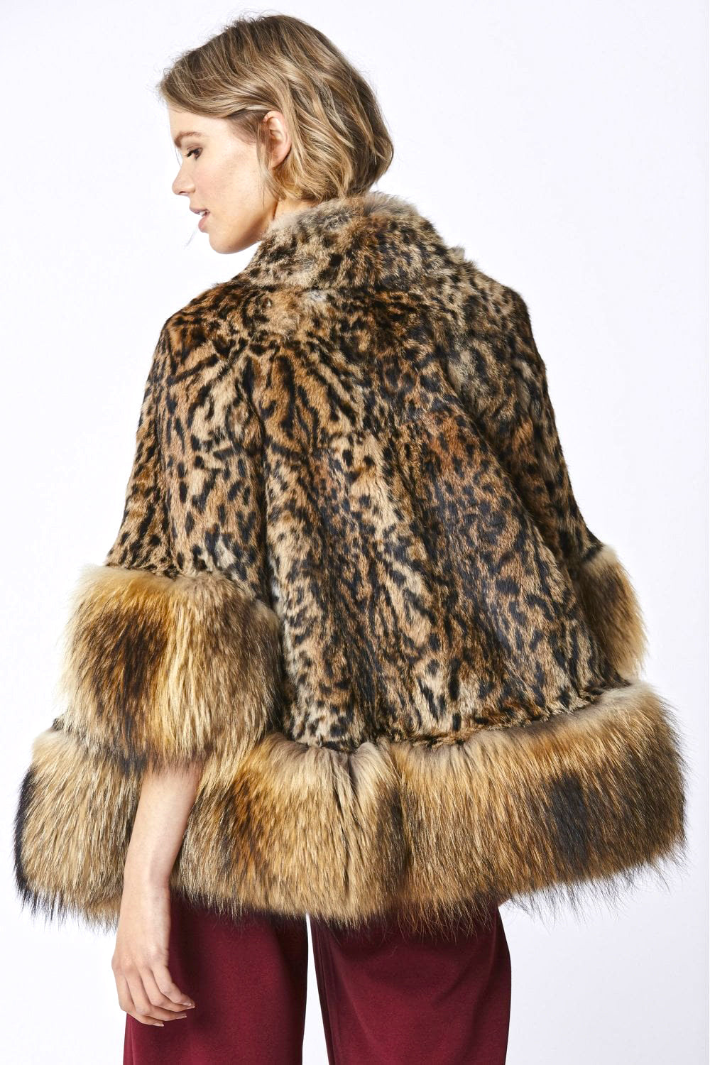 Leopard print fur coat with red fox trim worn by a person on a white background