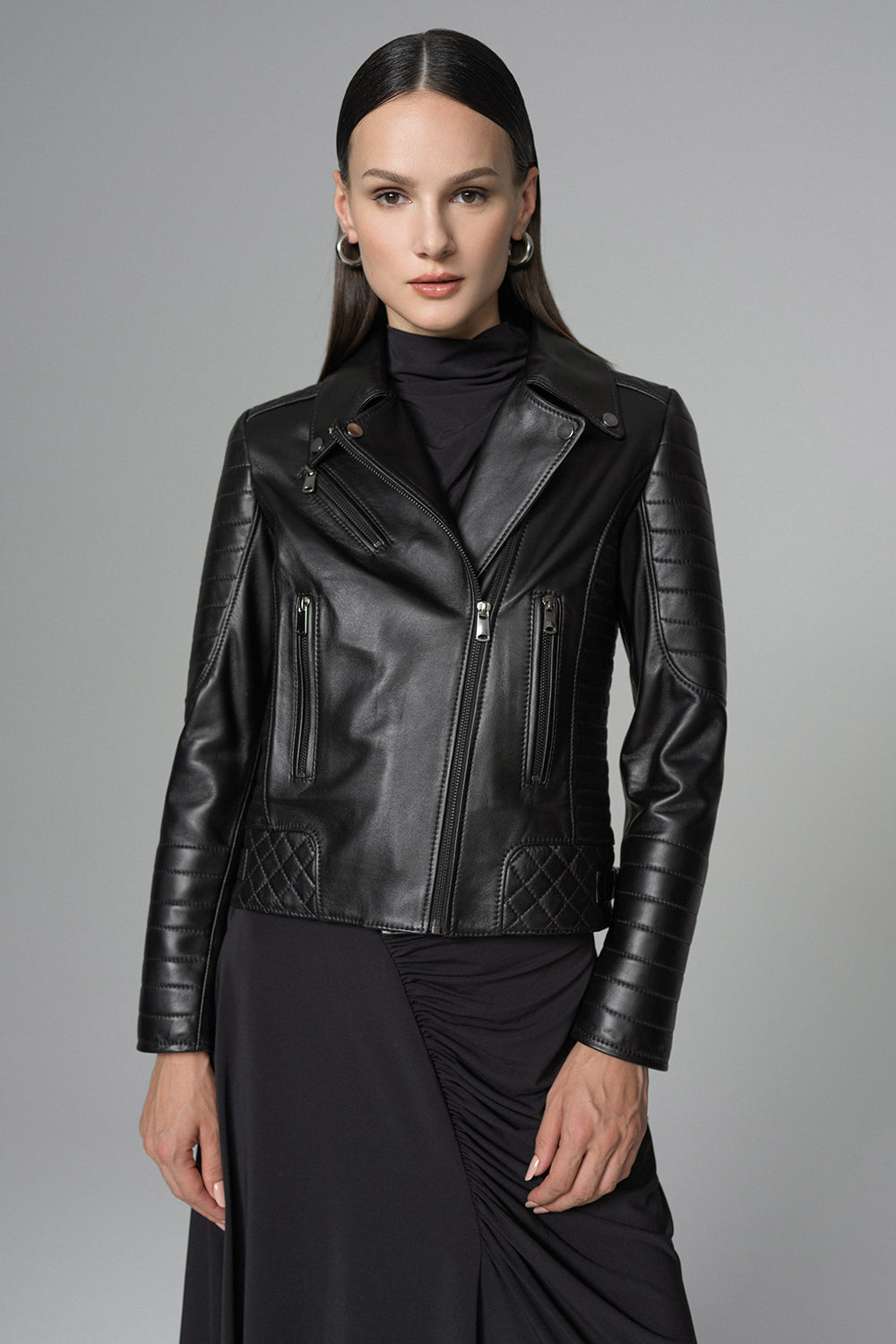 Woman wearing a black leather jacket against a gray background