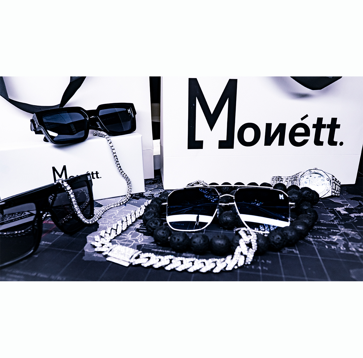 Black sunglasses with a chain and 'Monett' branding on a white background