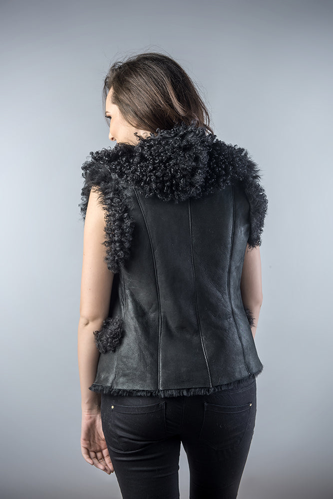 Person wearing a black leather vest with pom-pom details on a gray background