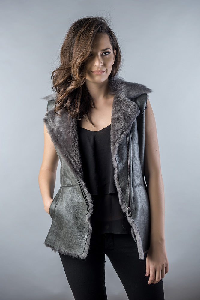 Woman wearing a gray vest with fur trim against a plain background