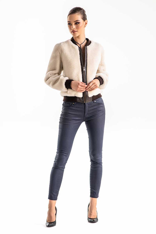 Woman wearing a beige jacket and dark jeans on a white background