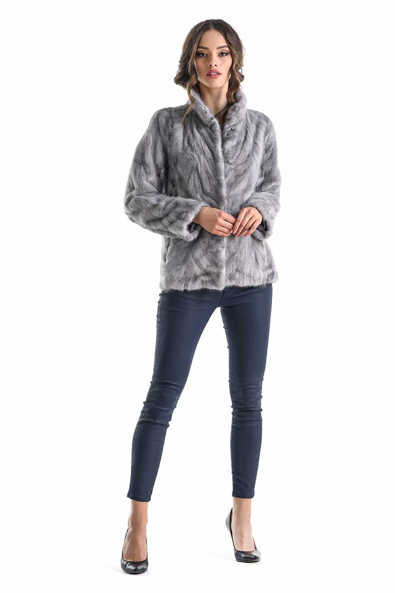 Woman wearing a gray fur coat and blue jeans on a white background
