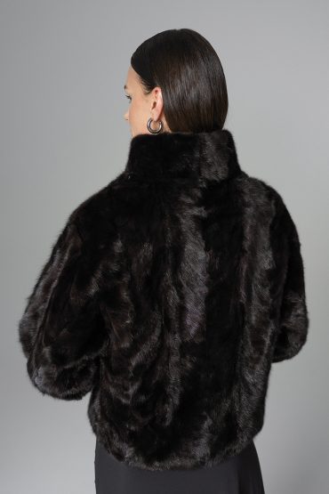 Woman wearing a black fur coat against a gray background