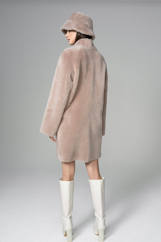 Person wearing a long pink coat and white boots on a gray background