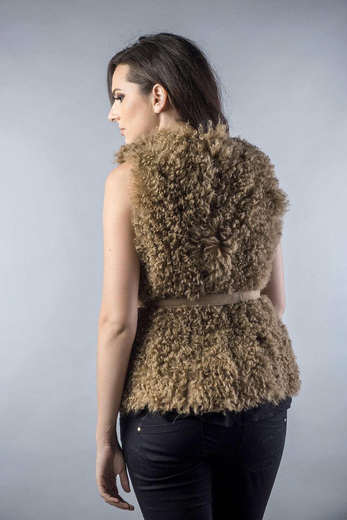 Woman wearing a brown fur vest against a gray background