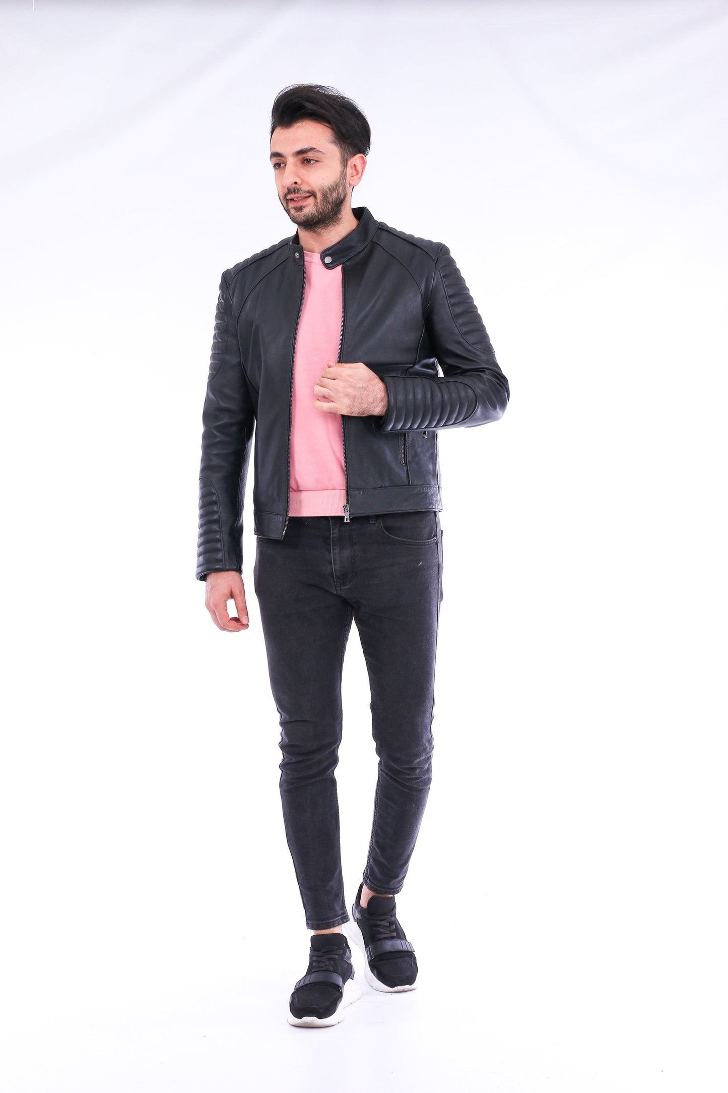 Man wearing a black leather jacket and pink shirt on a white background