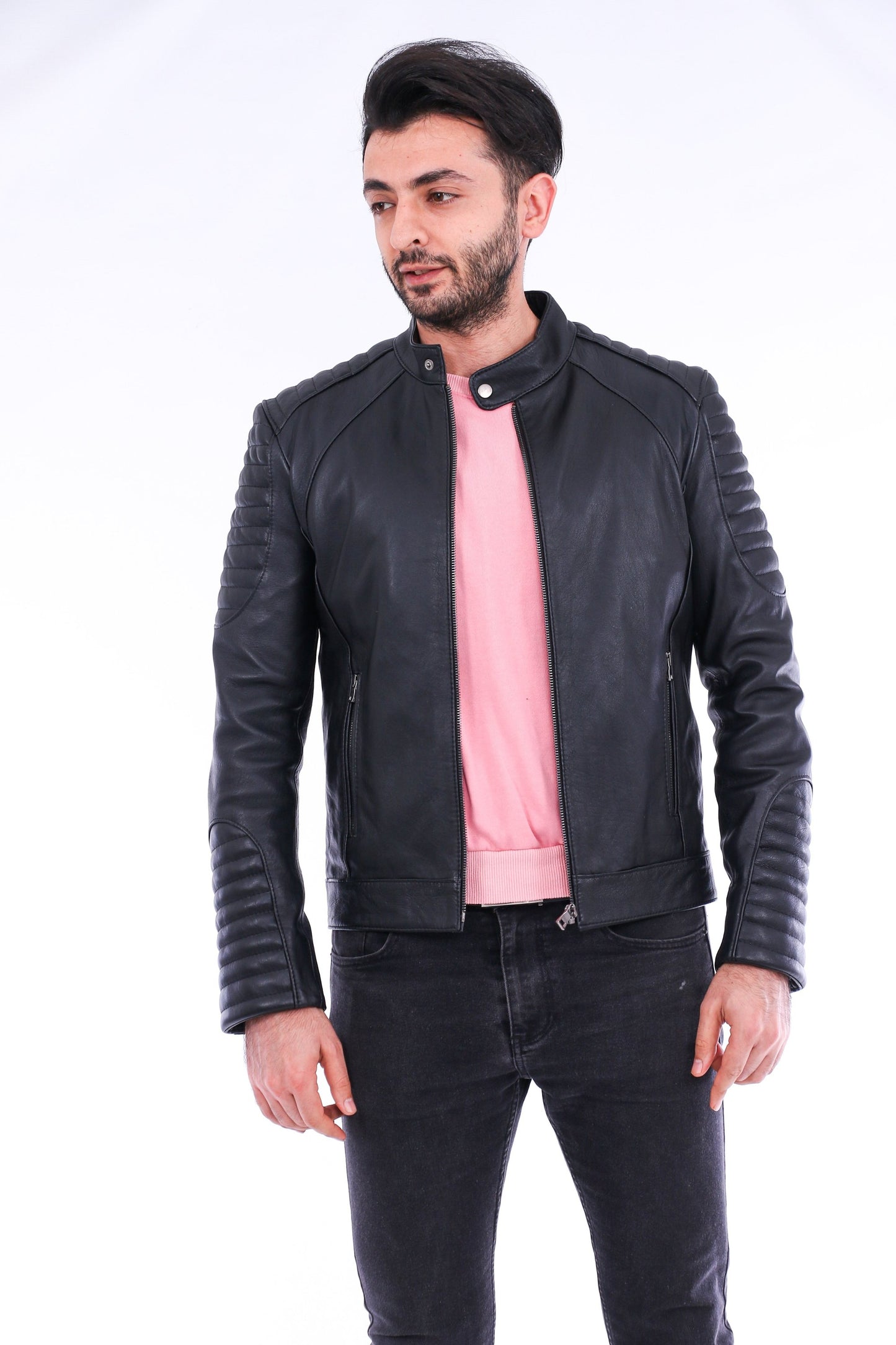 Man wearing a black leather jacket over a pink shirt on a white background
