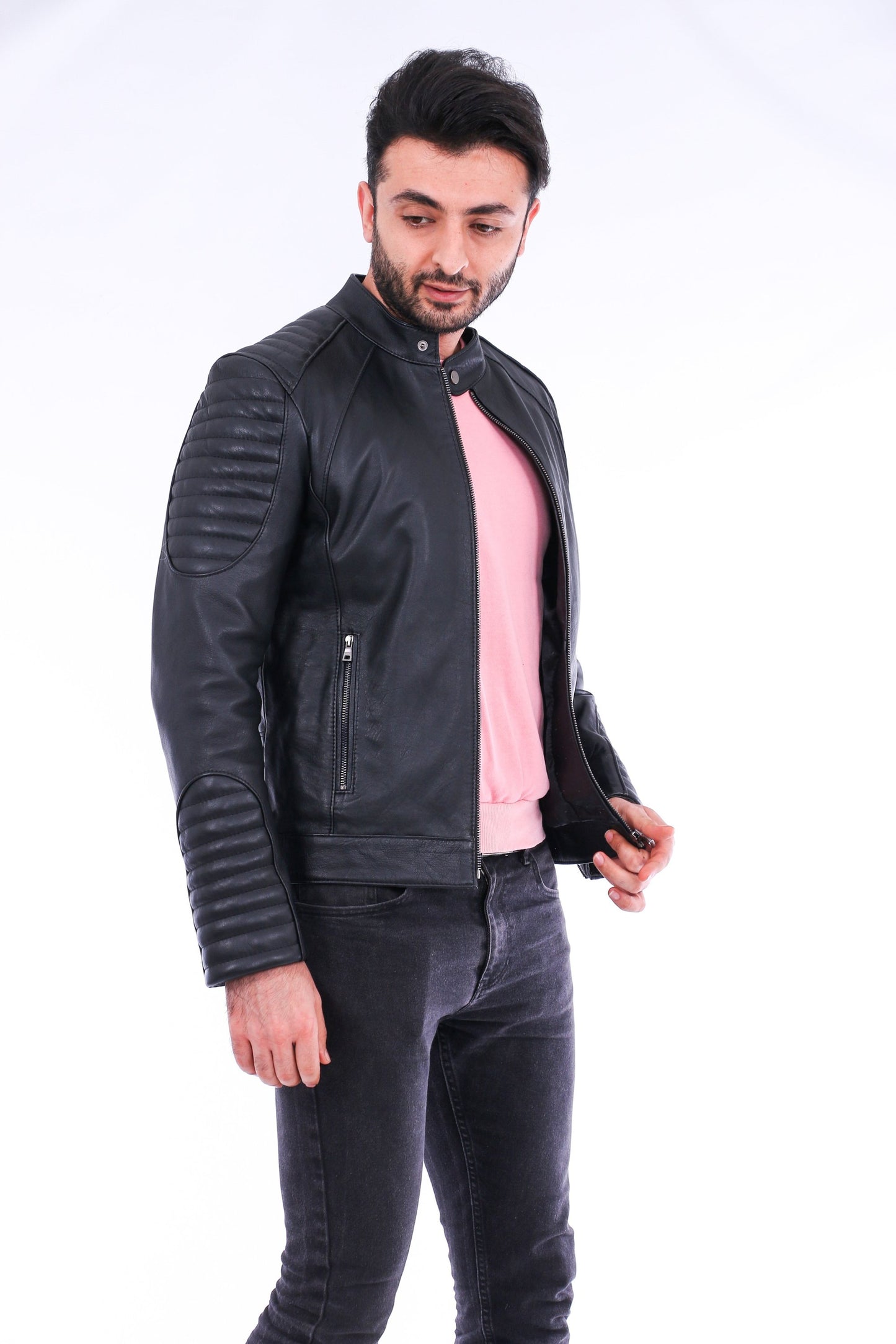 Man wearing a black leather jacket over a pink shirt on a white background