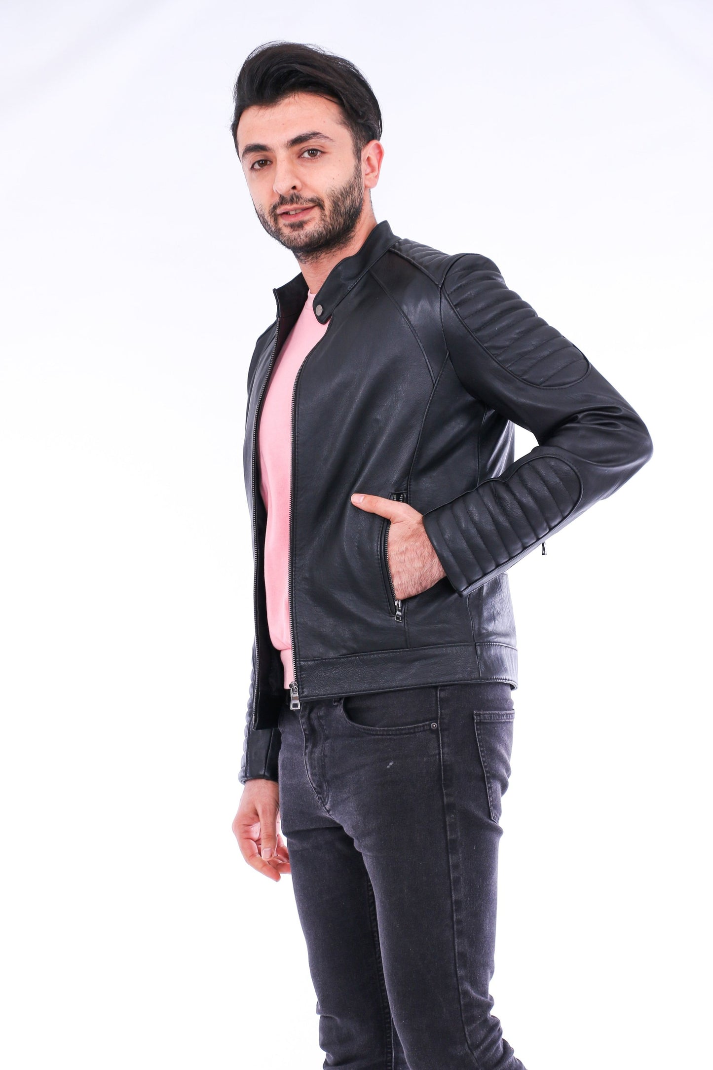 Man wearing a black leather jacket over a pink shirt on a white background