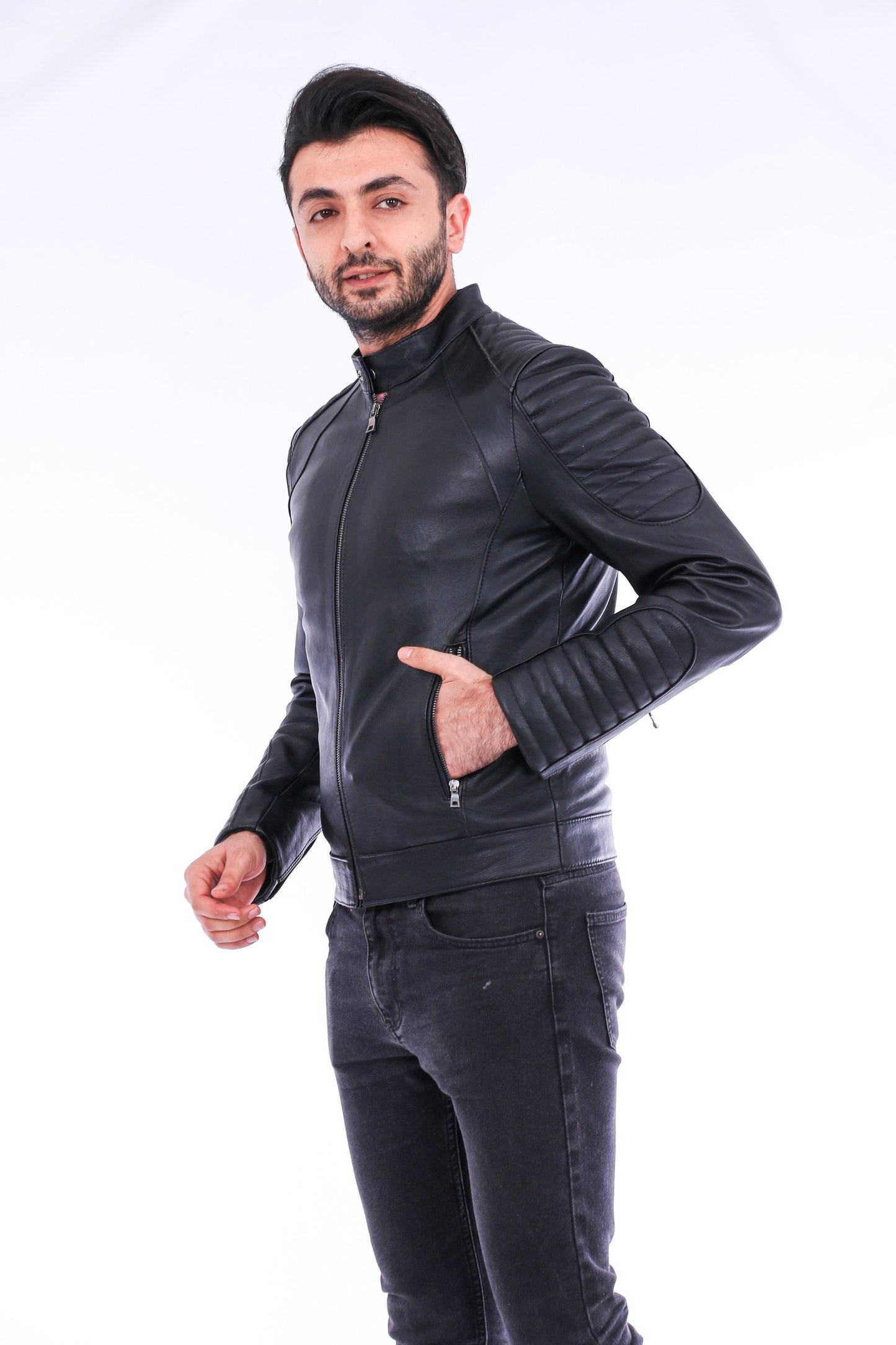 Man wearing a black leather jacket and dark jeans on a white background