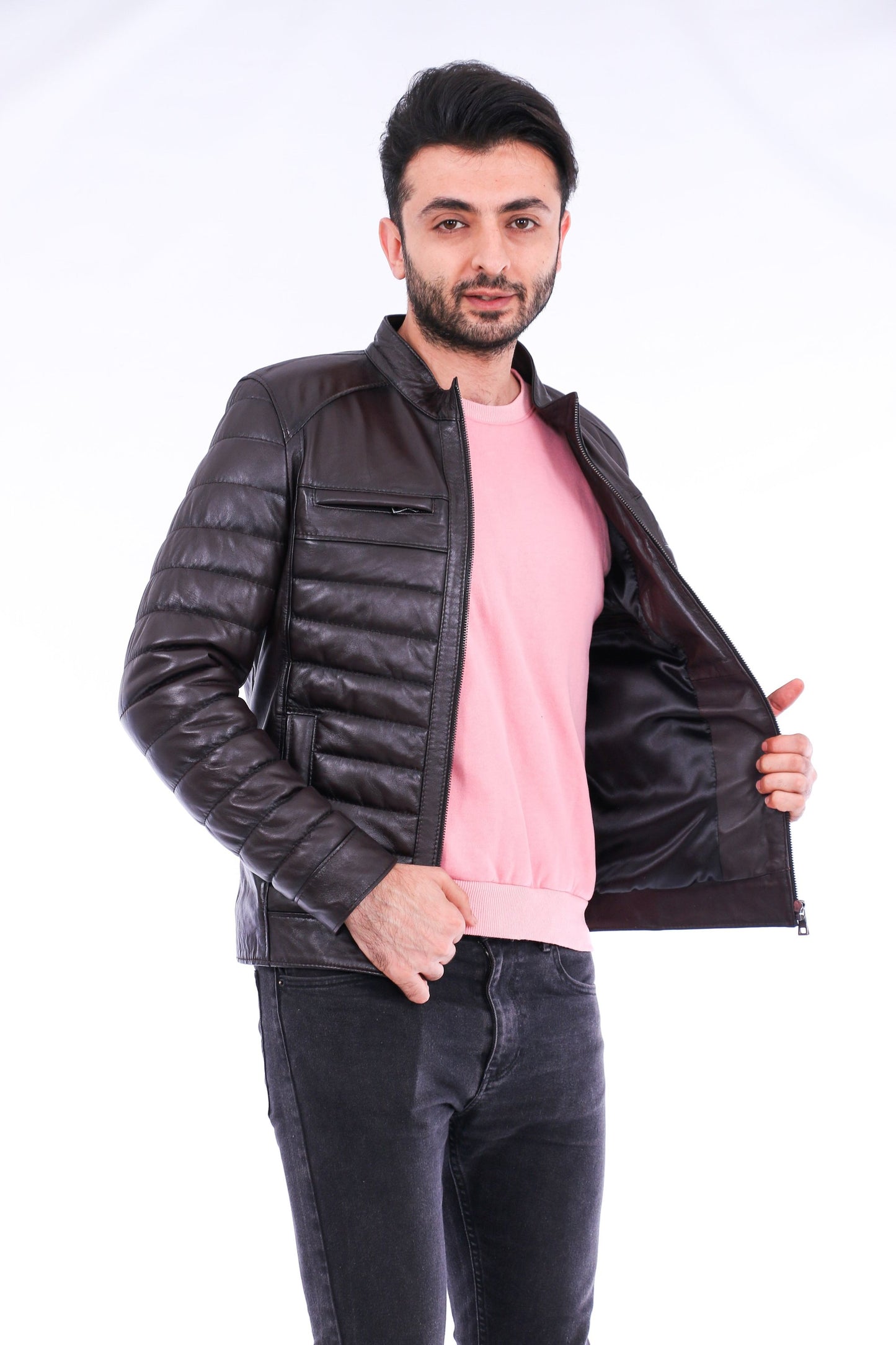 Man wearing a black leather jacket over a pink shirt on a white background