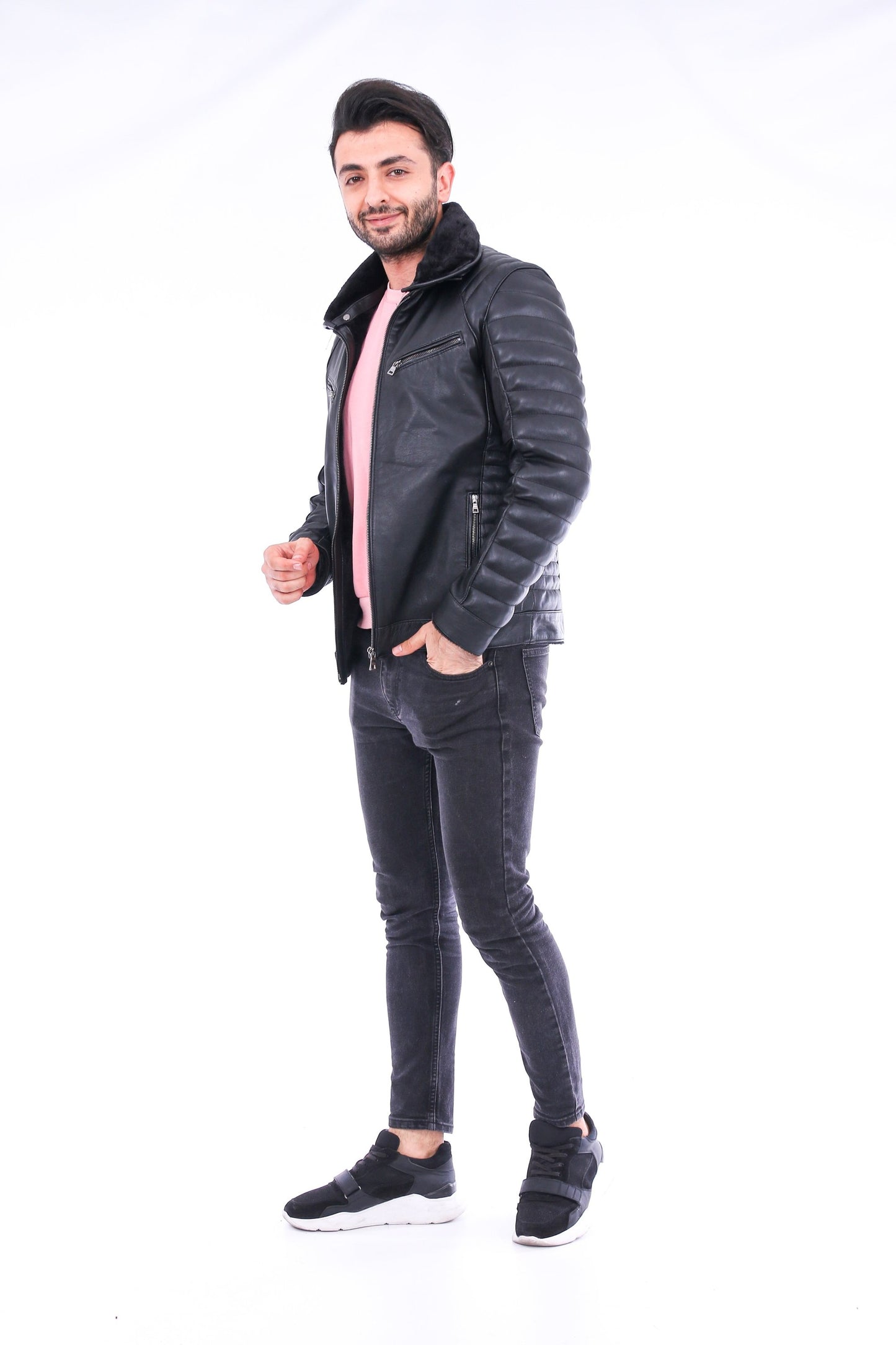 Man wearing a black leather jacket and jeans on a white background