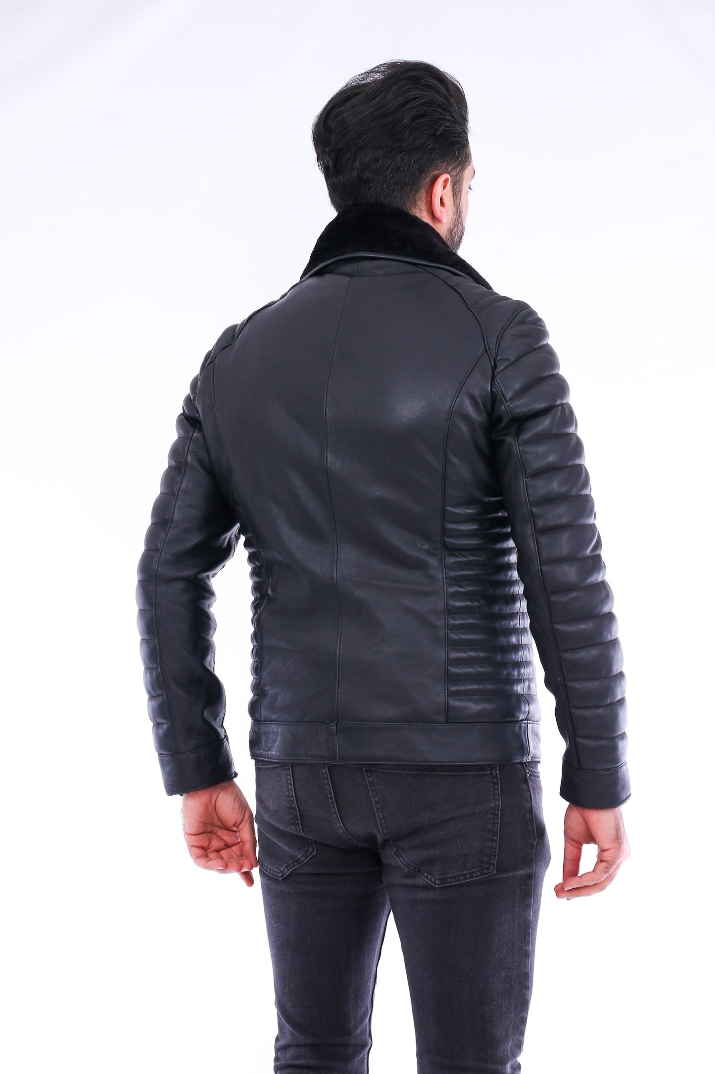 Man wearing a black leather jacket and pants on a white background