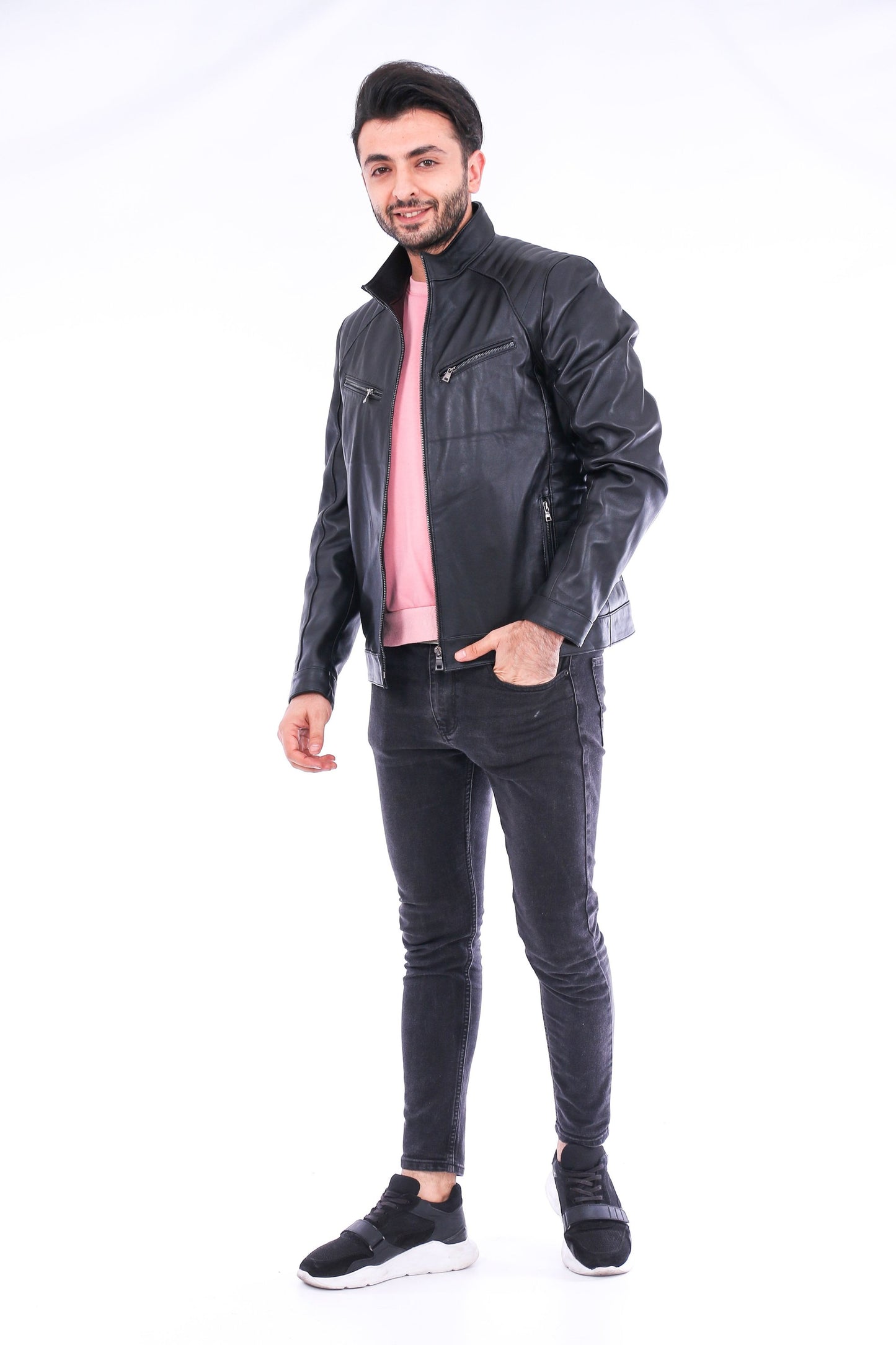 Man wearing a black leather jacket and dark jeans on a white background