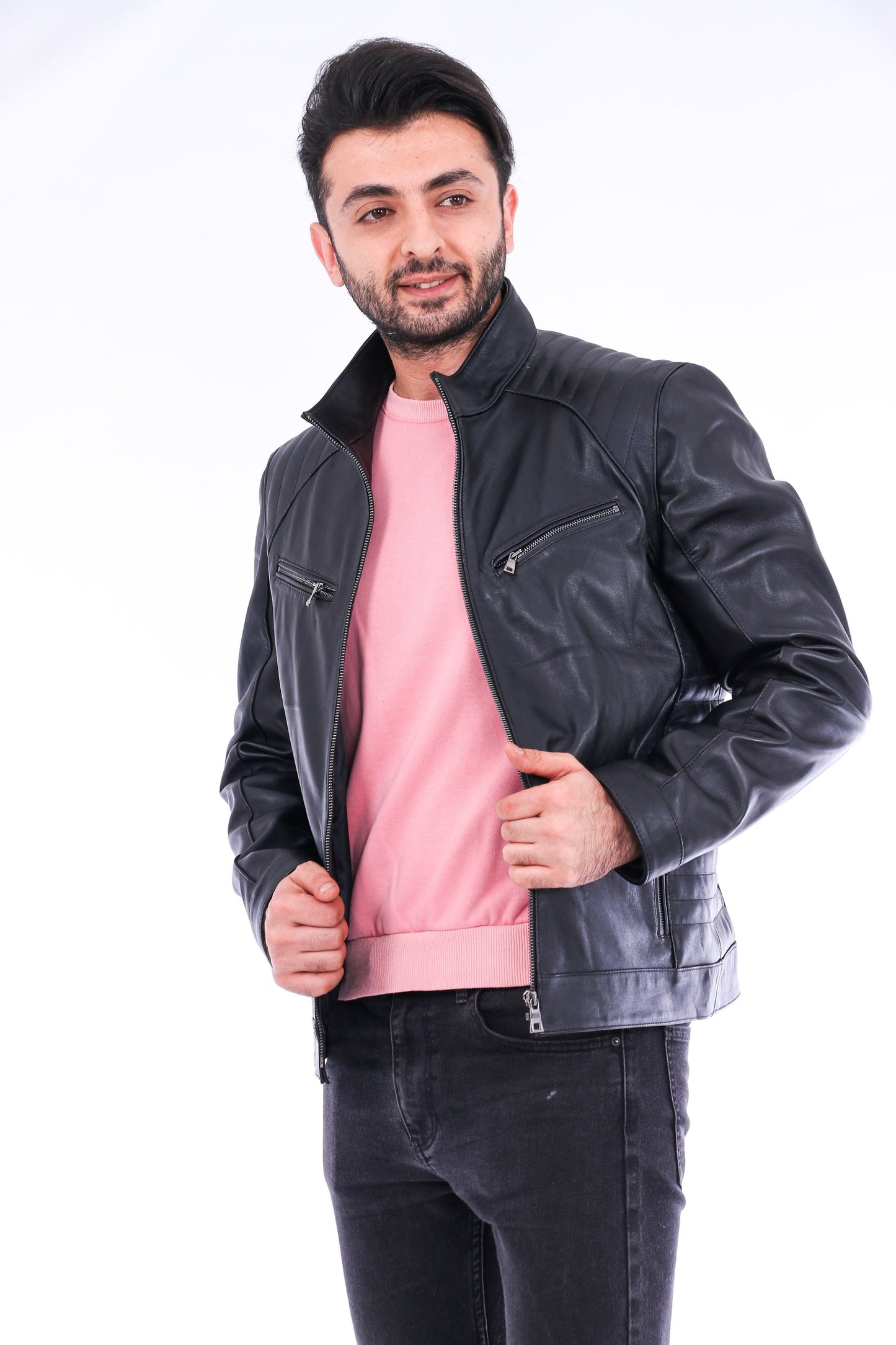 Man wearing a black leather jacket over a pink shirt on a white background
