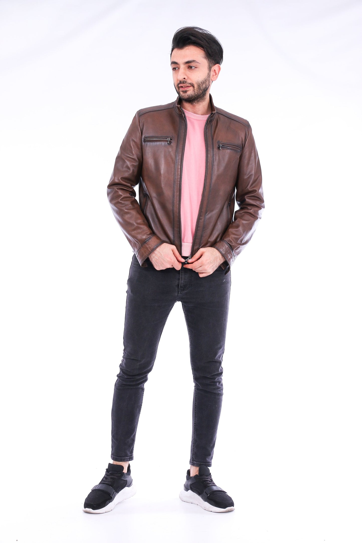 Man wearing a brown leather jacket and black jeans on a white background