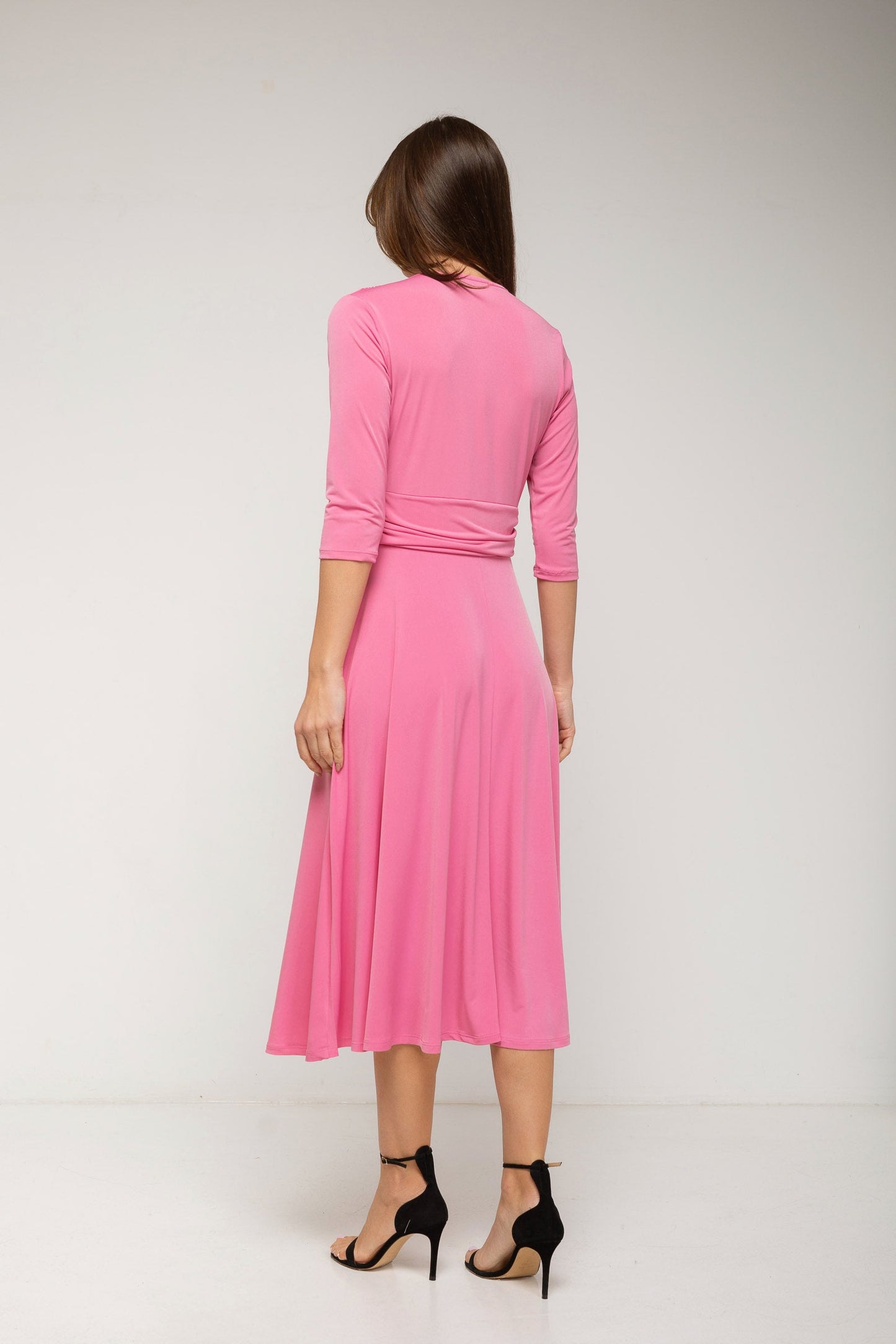 Woman wearing a pink dress with a plain background