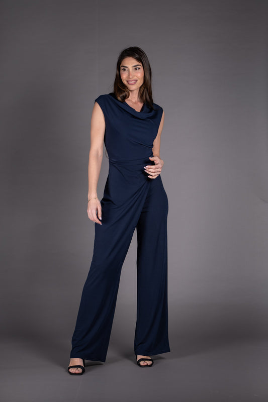 Woman wearing a navy blue jumpsuit against a gray background