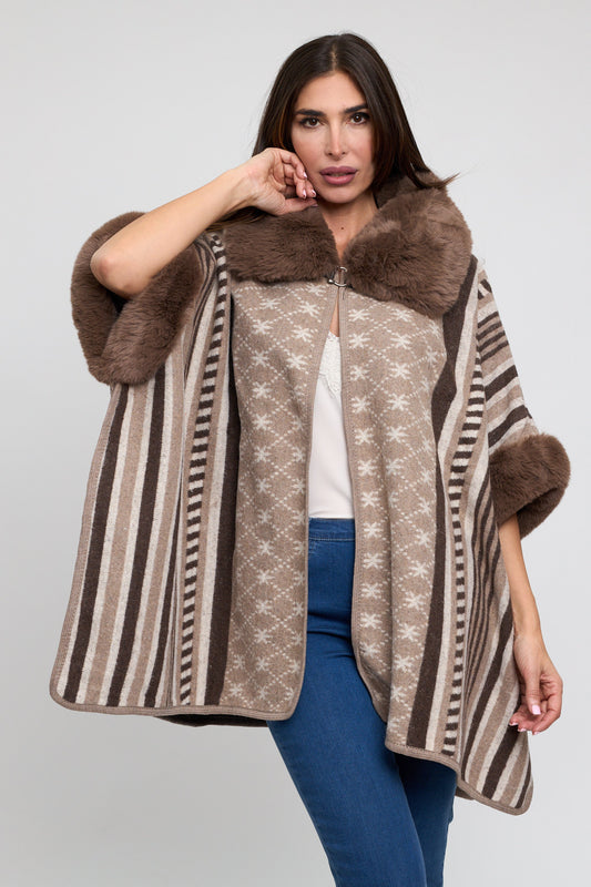 Woman wearing a patterned poncho with fur trim on a plain background