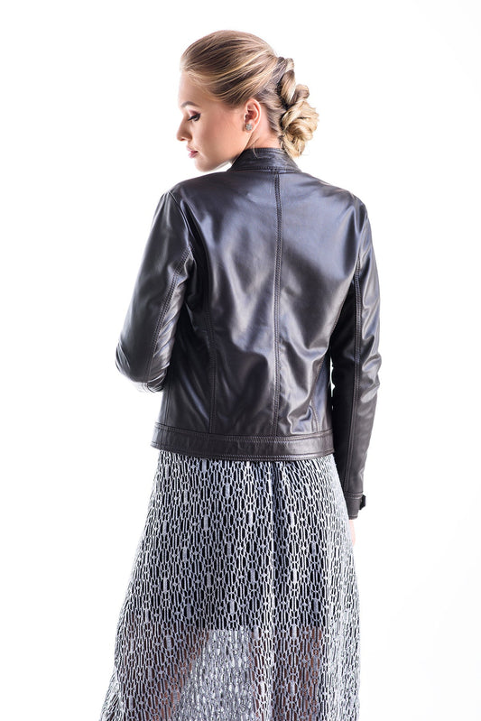 Woman wearing a brown leather jacket and patterned skirt on a white background