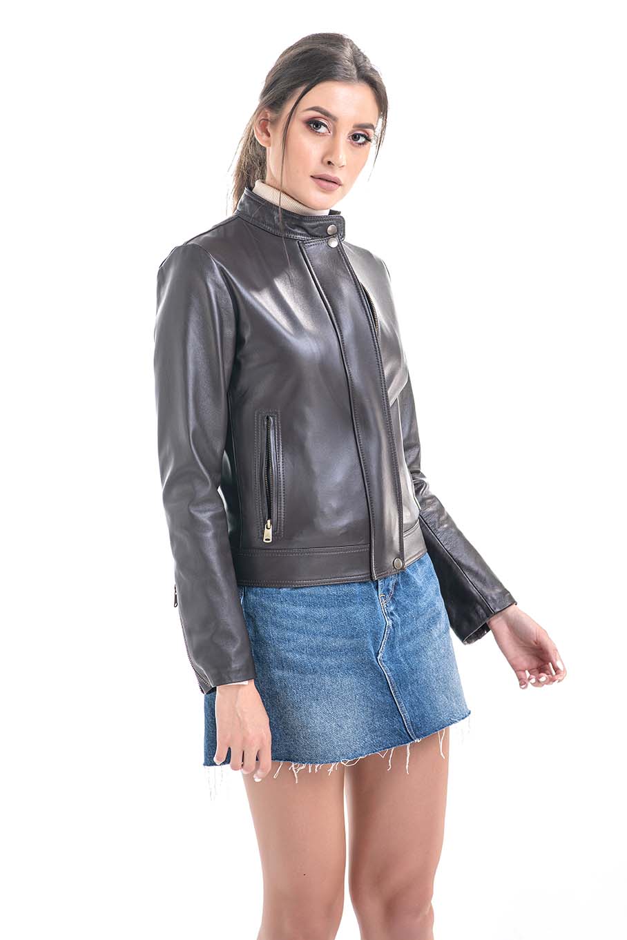 Woman wearing a brown leather jacket and blue denim skirt on a white background
