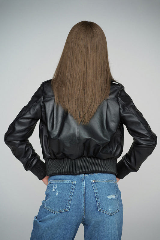 Person wearing a black leather jacket and blue jeans on a gray background