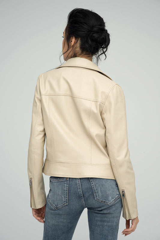 Person wearing a beige leather jacket and blue jeans on a gray background