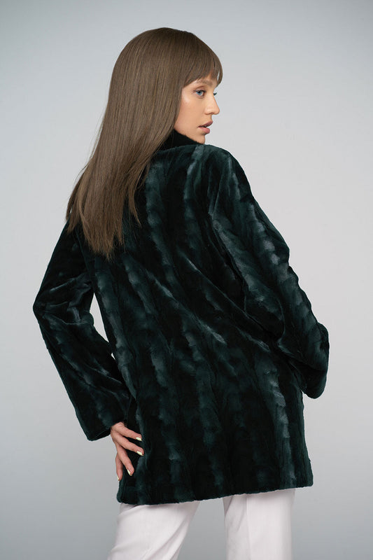 Woman wearing a dark green fur coat against a plain background