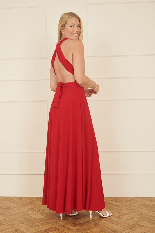 Woman wearing a red dress with an open back, standing against a plain background.