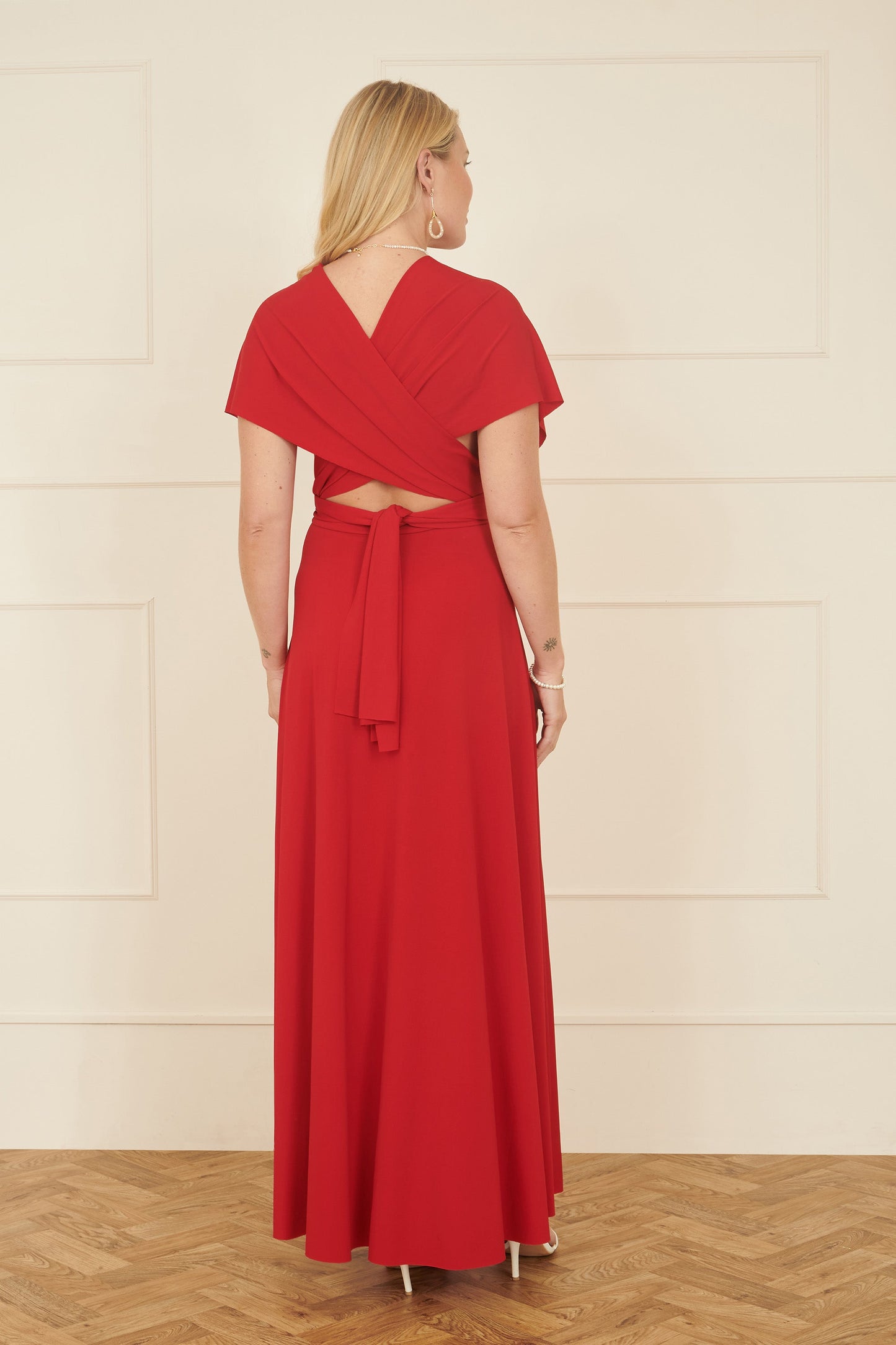 Woman wearing a red dress with a white wall background