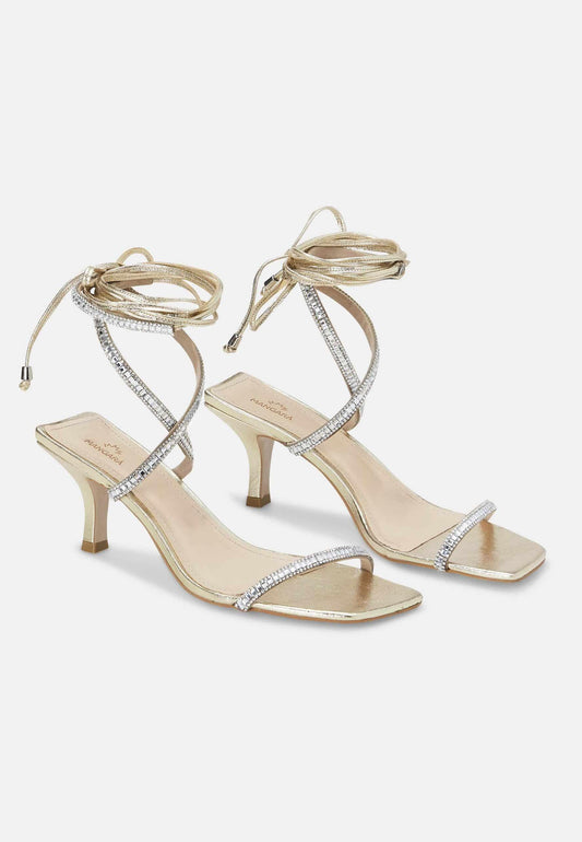 Gold high-heeled sandals with rhinestone detailing on a white background