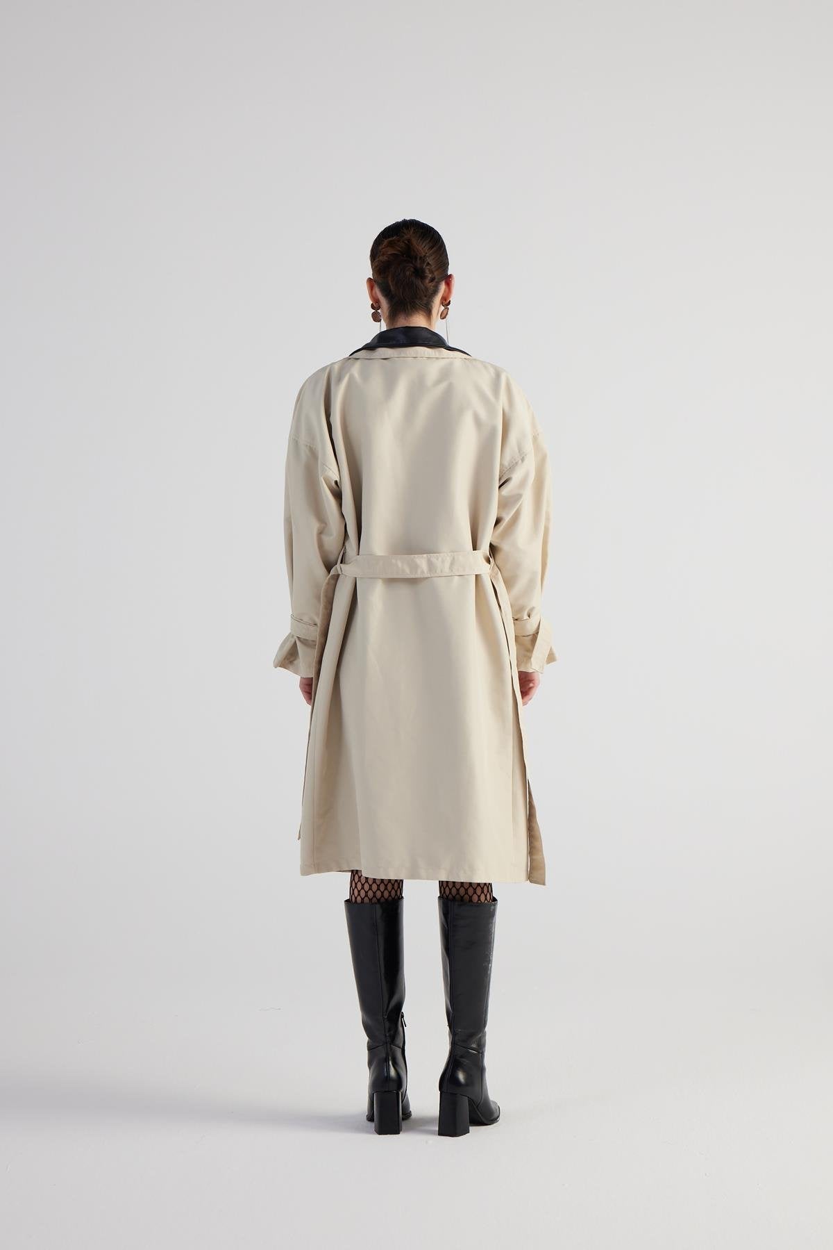 Person wearing a beige trench coat on a white background