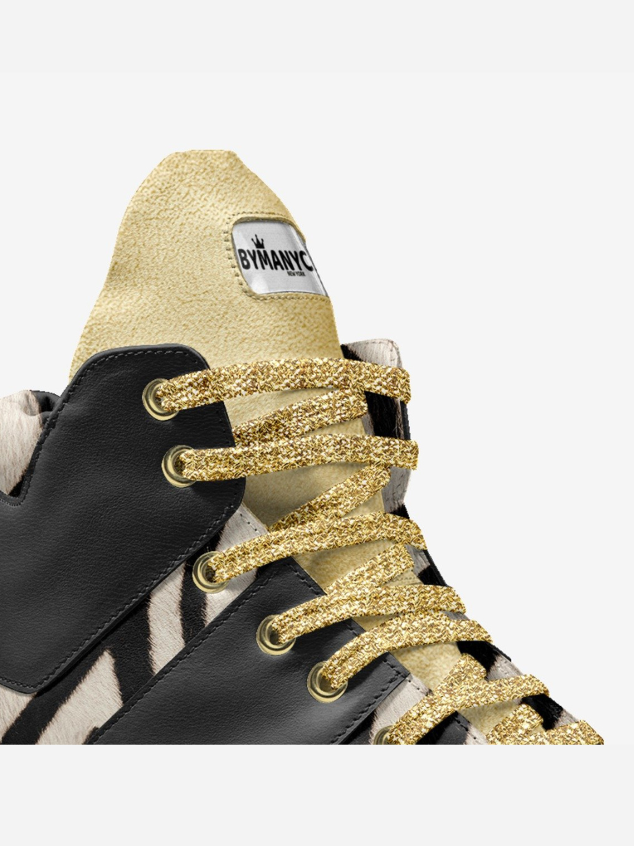 Close-up of a sneaker with gold glitter laces and a visible brand label on a white background.