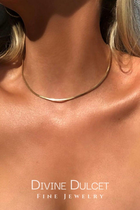 Close-up of a gold necklace on a person's neck with 'Divine Dulcet Fine Jewelry' branding.