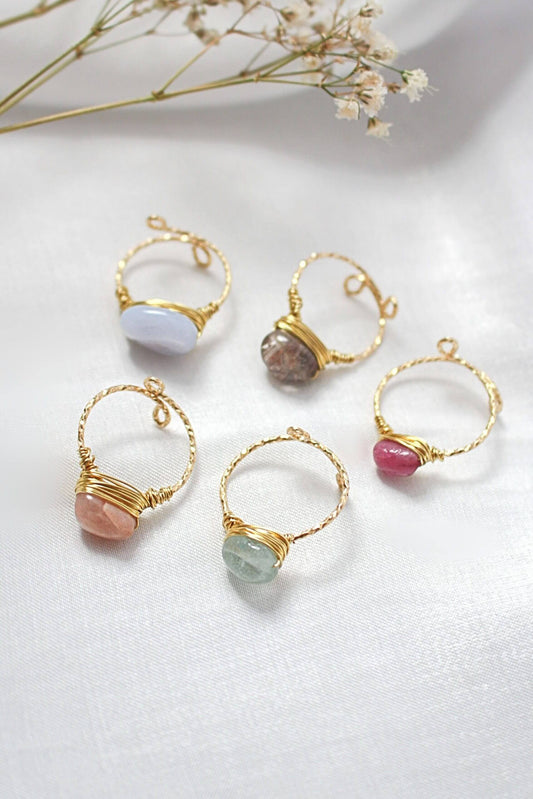 Gold hoop earrings with various colored stones on a light background