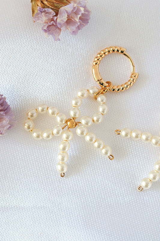 Pearl bow keychain on a white surface with purple flowers