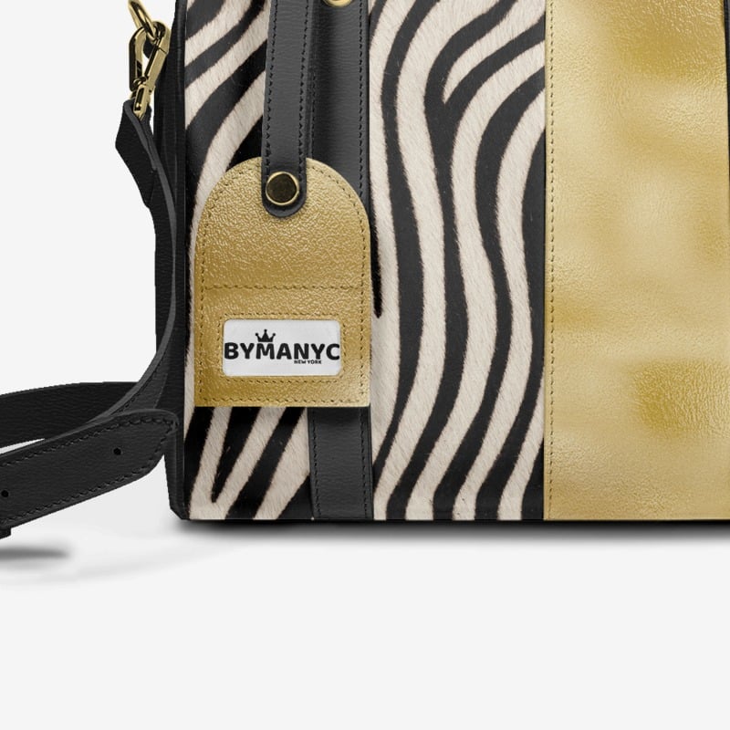 Handbag with zebra pattern and gold accents, featuring a ByManyC tag.