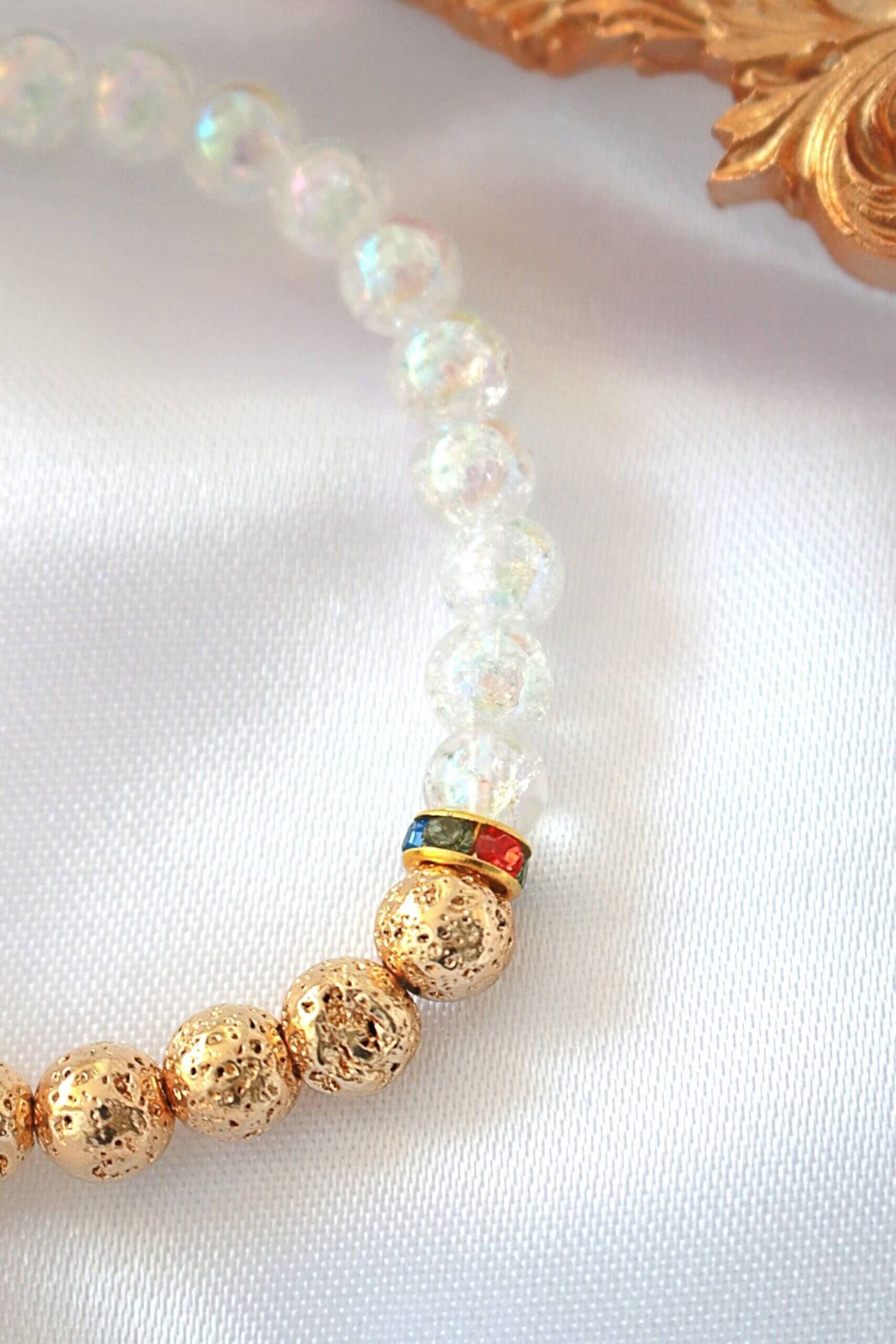 Pearl and gold beaded bracelet on a white fabric background