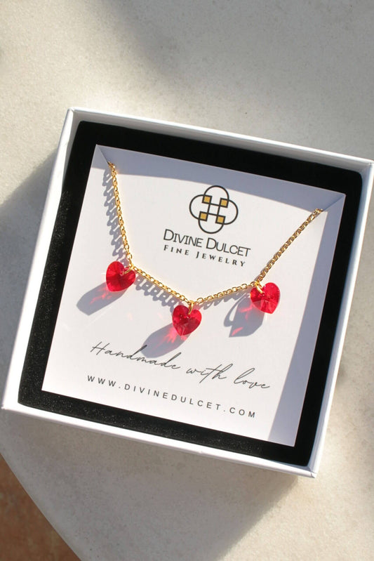 Necklace with red heart pendants in a 'Divine Dulcet Fine Jewelry' box.