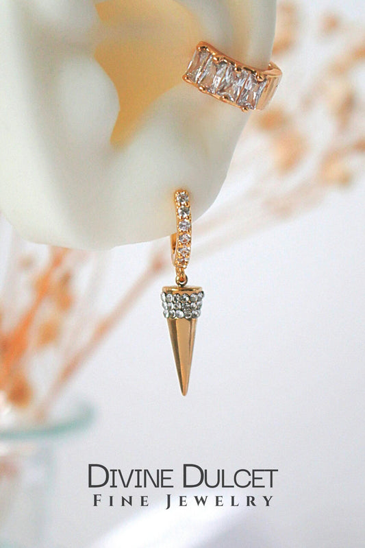 Gold earrings with diamond accents on a blurred background, featuring the brand 'Divine Dulcet'.